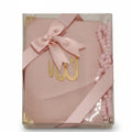 A pink book with a golden emblem on the cover, packaged with pink tassel-like decorations and a gold-colored ribbon.